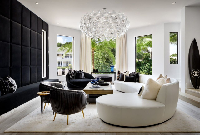 Lori Morris Design - A living room with white and black tones. A curved sofa, tree armchairs,  center table, a suspension lamp and a view outside. The sofa is white, the armchairs black and the center table a black and beige combination.