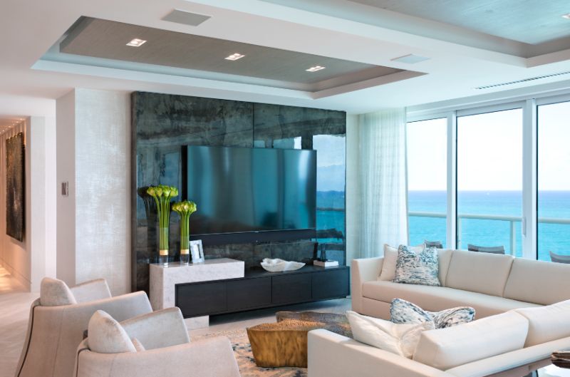 Sarah-Z-Designs - A room with a large sofa, two armchairs in white tones and a gold center table.